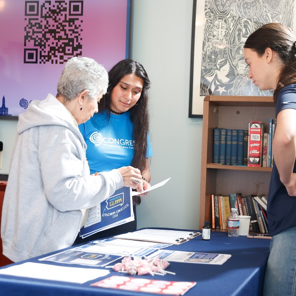 Three people standing around a table full of voter education resources