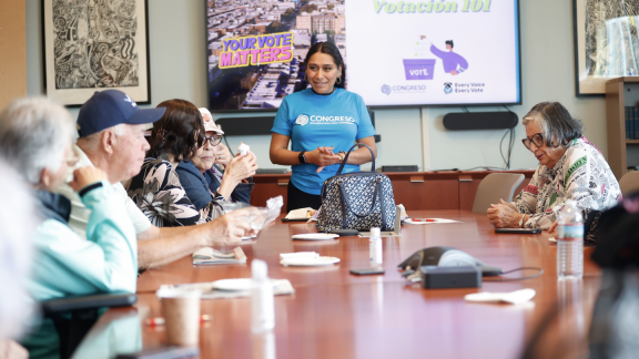 Woman giving a presentation to people seated around a table