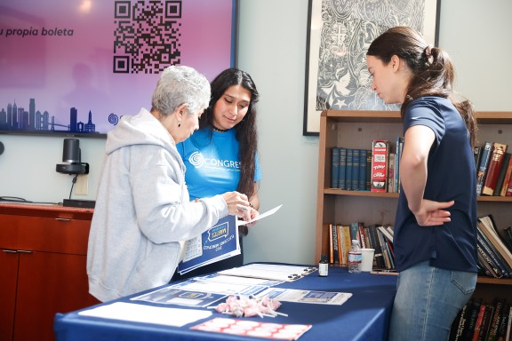 Three people standing around a table full of voter education resources