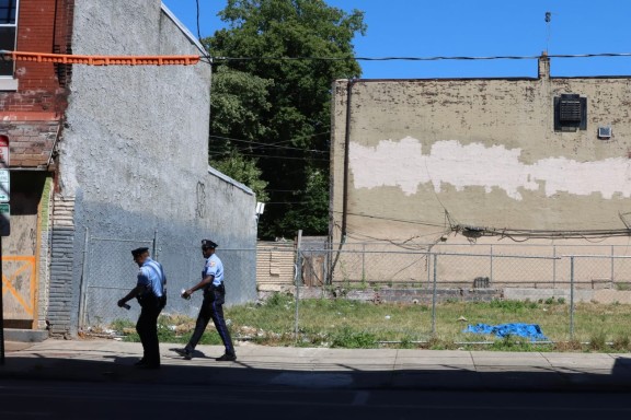 Two police officers walk past empty lot in Kensington neighborhood