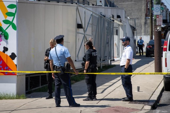 Police officers standing on a sidewalk with caution tape in front of them