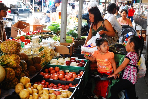 Woman and her children shopping for fruit at an outdoor market