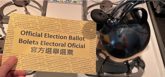 An official election ballot envelope being held near the spout of a tea kette