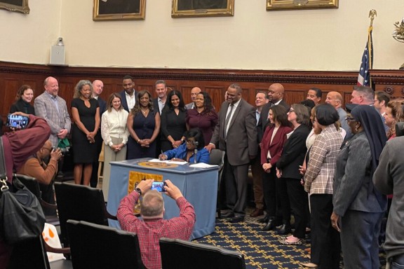 Mayor Cherelle Parker signing a paper with city officials standing around her