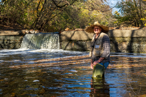 Erik Silldorff stands in Cobbs Creek in front of the Woodland Dam