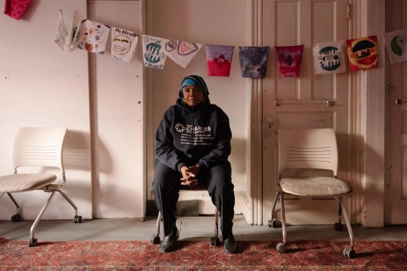 Movita Johnson-Harrell sitting in a chair in a white room with decorative flags above her