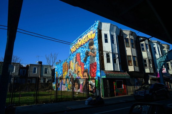 A bright colored mural of children on the side of row homes in Kensington, Philadelphia