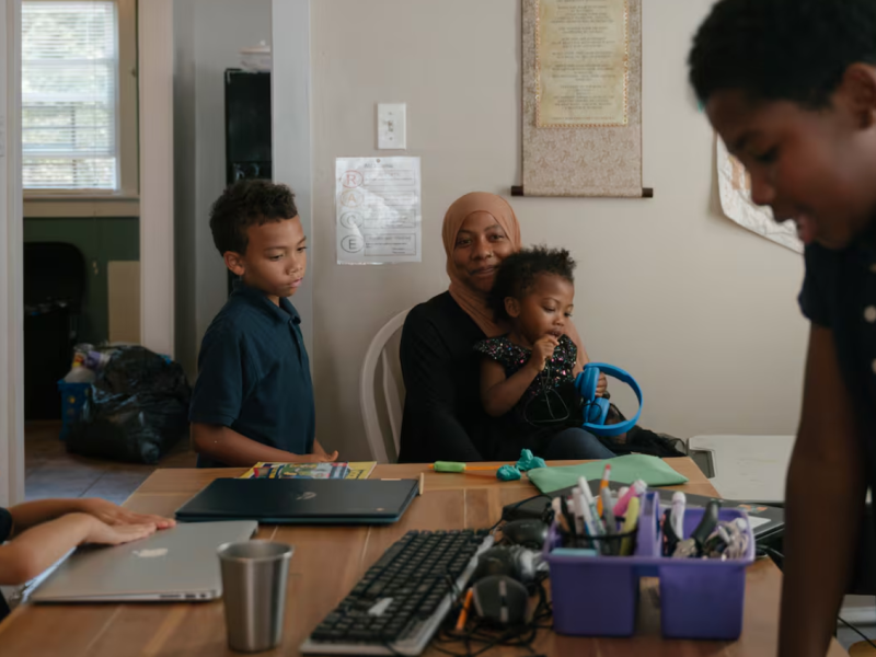 Sameerah Abdullah holds her daughter Maimoonah Abdul Hakeem, 3, while her children Asiyah Jones (left), 6, Dawud Jones, 7, and Musa Moore, 9, do schoolwork in their home in Philadelphia