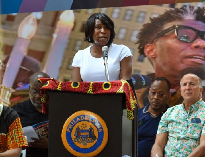 Celena Morrison-McLean speaking in front of a podium during a street dedication for Michael Hinson, Jr.