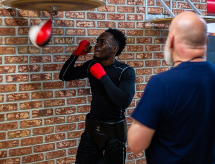 a boxing trainer and trainee using punching balloon